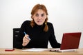 Shocked serious young office worker woman sitting behind working desk with laptop computer, cell phone and notebook Royalty Free Stock Photo