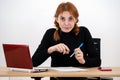 Shocked serious young office worker woman sitting behind working desk with laptop computer, cell phone and notebook Royalty Free Stock Photo