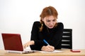 Shocked serious young office worker woman sitting behind working desk with laptop computer, cell phone and notebook Royalty Free Stock Photo