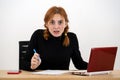 Shocked serious young office worker woman sitting behind working desk with laptop computer, cell phone and notebook Royalty Free Stock Photo