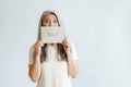 Shocked silver haired Asian lady holds card with word Sale on light grey background