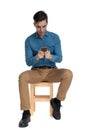 Shocked smart casual man holding phone and sitting Royalty Free Stock Photo