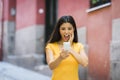 Shocked and surprised attractive young latin woman texting and talking on her smart cell phone Royalty Free Stock Photo