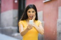 Shocked and surprised attractive young latin woman texting and talking on her smart cell phone Royalty Free Stock Photo