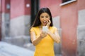 Shocked and surprised attractive young latin woman texting and talking on her smart cell phone Royalty Free Stock Photo