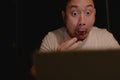 Shocked and surprised face of Asian man using laptop at night. Royalty Free Stock Photo
