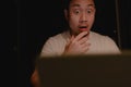 Shocked and surprised face of Asian man using laptop at night. Royalty Free Stock Photo