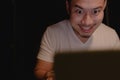 Shocked and surprised funny face of man watch the laptop alone at night.