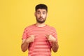 Shocked surprised man with beard in striped t-shirt pointing fingers at himself looking at camera with big eyes, astonishment Royalty Free Stock Photo