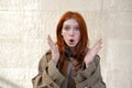 Shocked surprised teen redhead girl standing on urban wall background. Royalty Free Stock Photo