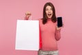 Shocked surprised woman holding paper bags and smartphone in hands, looking at camera with excitement, mobile shopping Royalty Free Stock Photo