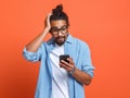 Shocked surprised young african american man looking at smartphone with stunned face expression Royalty Free Stock Photo