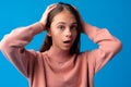 Shocked and surprised young teen girl against blue background Royalty Free Stock Photo