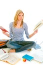 Shocked teen girl sitting on floor with books