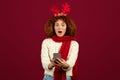 Shocked teen lady with deer antlers festive spirit of Christmas and New Year, look at phone