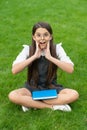 Shocked teen school girl sitting legs crossed on grass. School and education. Back to school Royalty Free Stock Photo