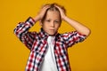 Shocked teenager european boy presses hands to head, isolated on yellow background