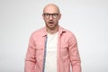 Shocked, upset bald man with glasses in a stupor, emotionally opened mouth and stares at the camera in disbelief. Royalty Free Stock Photo