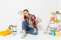 Shocked upset sad woman holds metal grocery baskets for shopping. Instruments for renovation apartment isolated on white Royalty Free Stock Photo