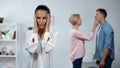 Shocked wife on foreground, mother-in-law wiping husbands mouth, overprotection Royalty Free Stock Photo