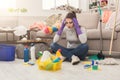 Shocked woman cleaning house with lots of tools