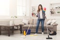 Shocked woman cleaning house with lots of tools