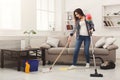 Shocked woman cleaning house with lots of tools