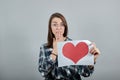 Shocked woman with glasses holds piece of paper with red heart in her hand Royalty Free Stock Photo