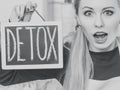 Shocked woman holding board with detox sign