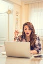 Shocked woman holding coffee cup and looking at laptop. Royalty Free Stock Photo