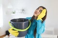 Shocked Woman Looks at the Ceiling While Collecting Water Which Leaks in the Living Room at Home. Worried Woman Holding Bucket Royalty Free Stock Photo