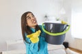 Shocked Woman Looks at the Ceiling While Collecting Water Which Leaks in the Living Room at Home. Worried Woman Holding Bucket Royalty Free Stock Photo