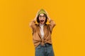 Shocked woman raising hands up and touching head over yellow studio background, emotional lady expressing amazement Royalty Free Stock Photo