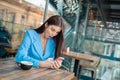 Shocked woman reading news on a phone sitting at a table Royalty Free Stock Photo