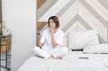 Shocked woman sitting on the bed and holding alarm clock Royalty Free Stock Photo