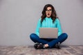 Shocked woman sitting on the floor with laptop