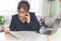 Shocked woman while talking on the phone and reading work documents - Mature woman puzzled while working from home - remote Royalty Free Stock Photo