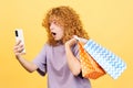 Shocked woman using the mobile while holing shopping bags Royalty Free Stock Photo