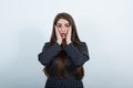 Shocked woman wearing black dress with white polka dot, keeping hands on cheeks. Royalty Free Stock Photo