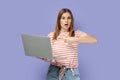 Shocked woman working on laptop, looking at camera and pointing at display with finger. Royalty Free Stock Photo