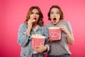 Shocked women friends eating popcorn watch film. Royalty Free Stock Photo