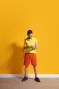 Young caucasian man using smartphone. Full body length portrait isolated over yellow background. Royalty Free Stock Photo