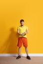 Young caucasian man using smartphone. Full body length portrait isolated over yellow background. Royalty Free Stock Photo