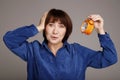 Shocked worried concerned middle aged mature brunette woman holding in hands clock put hand on head over grey background, studio Royalty Free Stock Photo