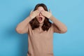 Shocked worried scared dark haired young woman years casual beige turtleneck, posing isolated on blue background, covering eyes