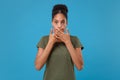 Shocked young african american woman girl in casual t-shirt posing isolated on bright blue wall background studio Royalty Free Stock Photo
