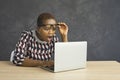 Shocked young African American woman looking open-mouthed at screen of her laptop