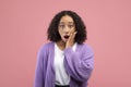 Shocked young African American woman touching her face and looking at camera in surprise over pink studio background Royalty Free Stock Photo