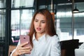 Shocked young Asian business woman with mobile smart phone in office. Internet of things concept Royalty Free Stock Photo