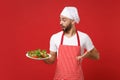 Shocked young bearded male chef cook or baker man in striped apron toque chefs hat posing isolated on red wall Royalty Free Stock Photo